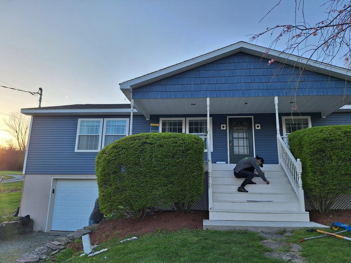 A front view of a blue, vinyl-sided home with white steps.